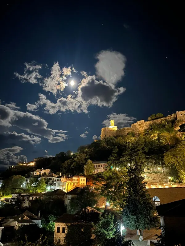 Gjirokastër castle and its clock tower lit up under a full moon
