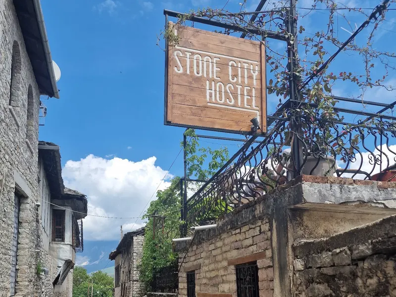 The hostel sign above a stone lane on a sunny day